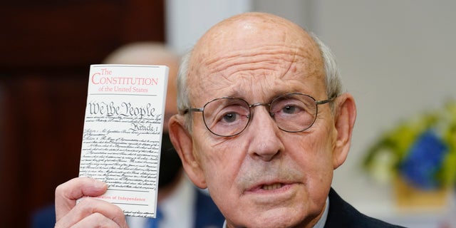 Supreme Court Associate Justice Stephen Breyer holds up a copy of the United States Constitution as he announces his retirement in the Roosevelt Room of the White House in Washington Jan. 27, 2022.