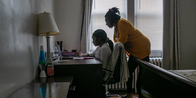Abigail Previlon, 13, takes part in remote distance learning on a Chromebook with the help of her mother Carlene at home on October 28, 2020 in Stamford, Connecticut. 