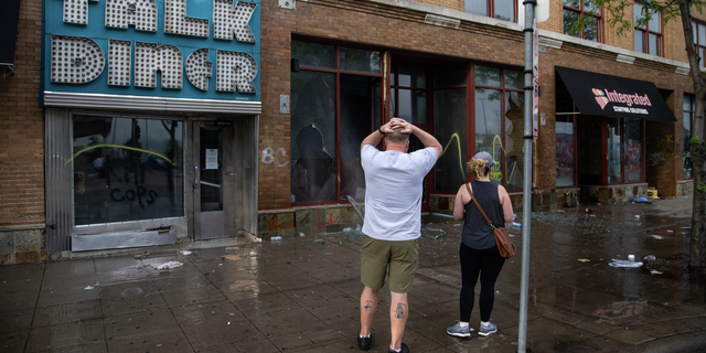 Charles Stotts and wife Kacey White, owners of Town Talk Diner on Lake Street in Minneapolis, watch as water pours out of their restaurant on Thursday, May 28, 2020. The building was looted the night before. "We have our whole lives tied into this restaurant," said Stotts. 
