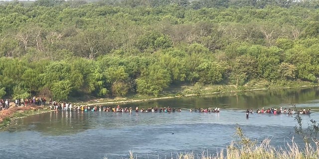 Migrants stream across the Texas border on July 13. Eight migrants were found dead Thursday and another 53 were taken into custody as they tried crossing the Rio Grande into Texas, authorities said. 