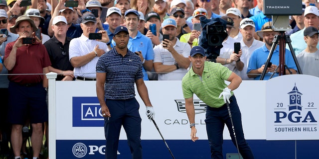 Rory McIlroy of Northern Ireland plays his tee shot on the 10th hole watched by his playing partner Tiger Woods of The United States during the first round of the 2022 PGA Championship at Southern Hills Country Club on May 19, 2022 in Tulsa, Oklahoma. 