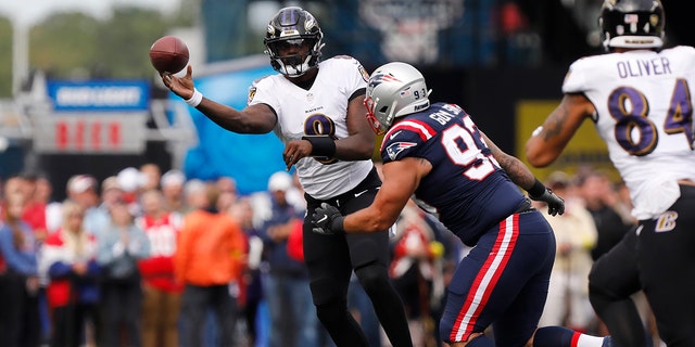 Baltimore Ravens quarterback Lamar Jackson, #8, passes under pressure from New England Patriots defensive end Lawrence Guy, #93, in the first half of an NFL football game, Sunday, Sept. 25, 2022, in Foxborough, Massachusetts. 