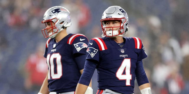 Mac Jones #10 and Bailey Zappe #4 of the New England Patriots stand on the field prior to the game against the Chicago Bears at Gillette Stadium on October 24, 2022 in Foxborough, Massachusetts.