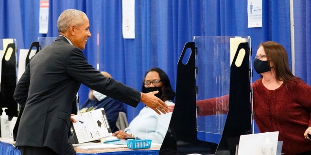 Former President Barack Obama shakes hands with a poll worker before casting his ballot at an early voting site on Oct. 17, 2022, in Chicago.