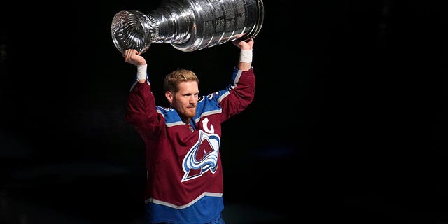 Colorado Avalanche left winger Gabriel Landeskog hoists the Stanley Cup for fans before the championship banner was lifted to the rafters at the team's NHL hockey game against the Chicago Blackhawks on Wednesday, Oct. 12, 2022, in Denver.