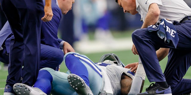 Dallas Cowboys running back Ezekiel Elliott lies on the ground while being attended by trainers during the game against the Detroit Lions on Oct. 23, 2022, in Arlington, Texas.