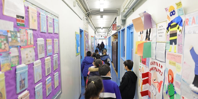 Students are led to their classroom by Marisa Wiezel (who is related to the photographer), a teacher at Yung Wing School P.S. 124 on March 07, 2022 in New York City. 