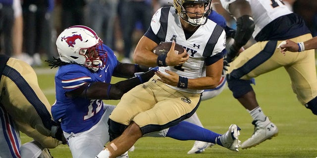 Navy quarterback Tai Lavatai (1) is grabbed by SMU defensive end David Abiara (10) during the first half of an NCAA college football game in Dallas, Friday, Oct. 14, 2022.