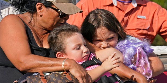 FILE - Yolanda Rios, left, holds her grandchildren Ava, 7, and Giovanni, 5, as as they are evacuated by airboat through floodwaters along the Peace River, to get to a hospital for medical care, in the aftermath of Hurricane Ian on Arcadia, Fla., Monday, Oct. 3, 2022. The devastation from Hurricane Ian has left schools shuttered indefinitely in parts of Florida, leaving storm-weary families anxious for word on when and how children can get back to classrooms. (AP Photo/Gerald Herbert, File)