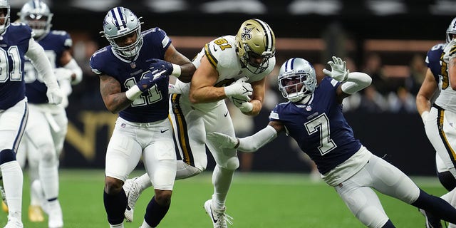 Micah Parsons (11) and Trevon Diggs (7) of the Dallas Cowboys tackle Nick Vannett of the New Orleans Saints on Dec. 2, 2021, in New Orleans.