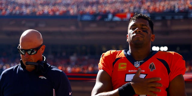 Head coach Nathaniel Hackett and Russell Wilson of the Broncos during the playing of the national anthem before the Houston Texans game at Empower Field At Mile High on Sept. 18, 2022, in Denver.