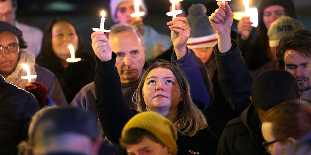 People hold a vigil at a makeshift memorial near the Club Q nightclub on November 20, 2022 in Colorado Springs, Colorado.