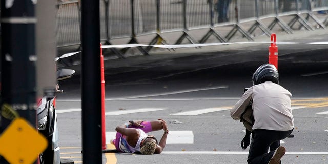 Daniel Do Nascimento of Brazil, left, lies on the pavement after collapsing during the New York City Marathon, Nov. 6, 2022, in New York.