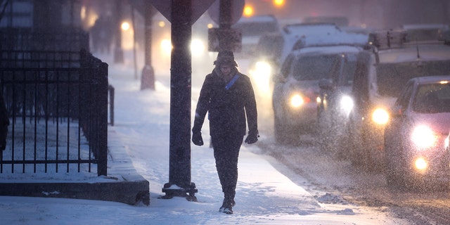A pedestrian navigates a snow-covered sidewalk as temperatures hang in the single-digits on Dec. 22, 2022 in Chicago, Illinois.