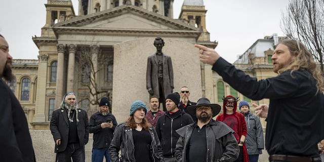 Minister Adam gathers with other members of the Satanic Temple of Illinois in front of the Abraham Lincoln statue on Dec. 6, 2022, outside the Illinois State Capitol in Springfield before installing their seasonal display alongside a Christmas tree and menorah inside the rotunda. (Brian Cassella/Chicago Tribune/Tribune News Service via Getty Images) 