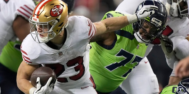 San Francisco 49ers running back Christian McCaffrey, #23, runs against Seattle Seahawks defensive tackle Quinton Jefferson during the second half of an NFL football game in Seattle, Thursday, Dec. 15, 2022.