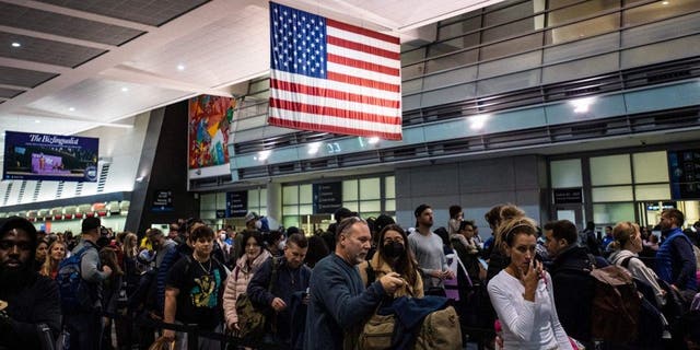 Travelers make their way through a security line at Logan International Airport in Boston, Massachusetts, on December 23, 2022. - A historic and brutal winter storm put some 240 million Americans under severe weather warnings Friday as the US faced holiday travel chaos, with thousands of flights cancelled and major highways closed. (Photo by Joseph Prezioso / AFP) (Photo by JOSEPH PREZIOSO/AFP via Getty Images)