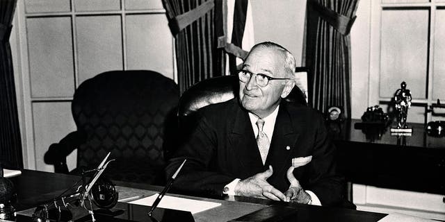 President Harry S. Truman seated in the White House with the sign "The Buck Stops Here" in the foreground, circa 1950. 