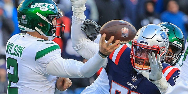 New England Patriots LB Josh Uche attempts to prevent New York Jets QB Zach Wilson from getting a pass attempt off.