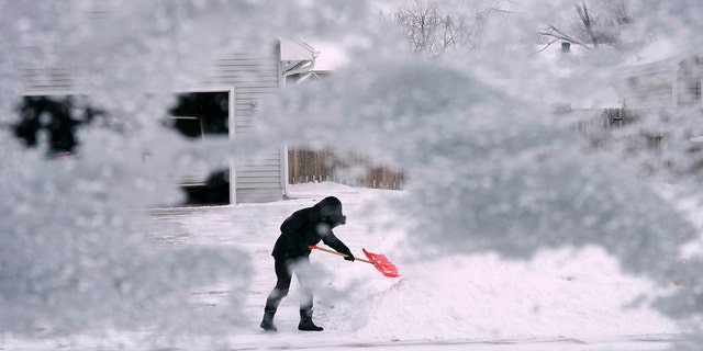 A local resident shovels snow off the end of a driveway, Thursday, Dec. 22, 2022, in Urbandale, Iowa. (AP Photo/Charlie Neibergall)
