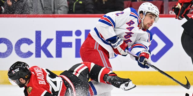 Filip Chytil #72 of the New York Rangers completes a shot on goal after colliding with Colin Blackwell #43 of the Chicago Blackhawks in the first period on December 18, 2022, at United Center in Chicago, Illinois.