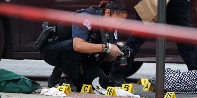 A Chicago police officer processes a crime scene. The city saw widespread gun violence during the holiday weekend, leaving seven people dead and 21 others wounded. 