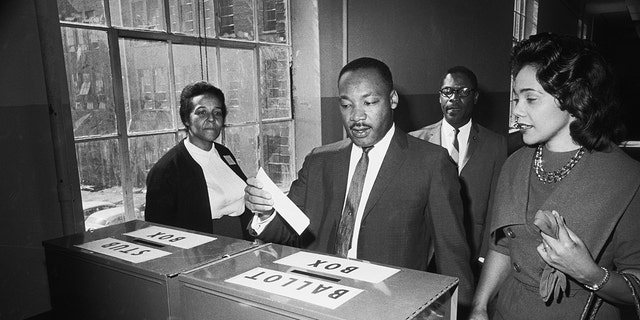 11/3/1964-Atlanta, GA: Dr Martin Luther King Jr votes as his wife, Coretta Scott King, waits her turn.