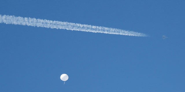 FILE PHOTO: A jet flies by a suspected Chinese spy balloon as it floats off the coast in Surfside Beach, South Carolina, U.S. February 4, 2023.  REUTERS/Randall Hill/File Photo
