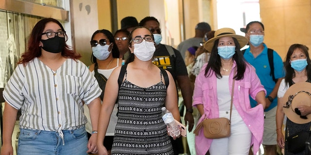 In this July 1, 2021, file photo, visitors wear masks as they walk in a shopping district in the Hollywood section of Los Angeles. 