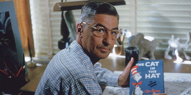 American author and illustrator Dr Seuss (Theodor Seuss Geisel, 1904 - 1991) sits at his drafting table in his home office with a copy of his book, 'The Cat in the Hat', La Jolla, California, April 25, 1957.  (Photo by Gene Lester/Getty Images)
