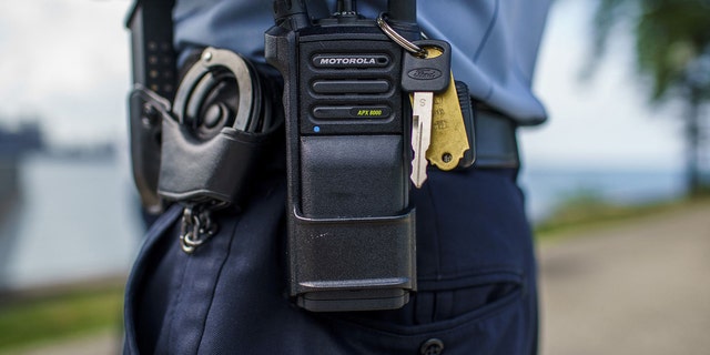 A Chicago police officer stands with a police radio near Oak Street Beach on Aug. 18 in Chicago.