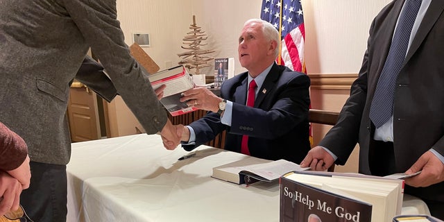 Former Vice President Mike Pence signs copies of his new autobiography "So Help Me God," at a book signing on Dec. 12, 2022 in Bedford, New Hampshire. 