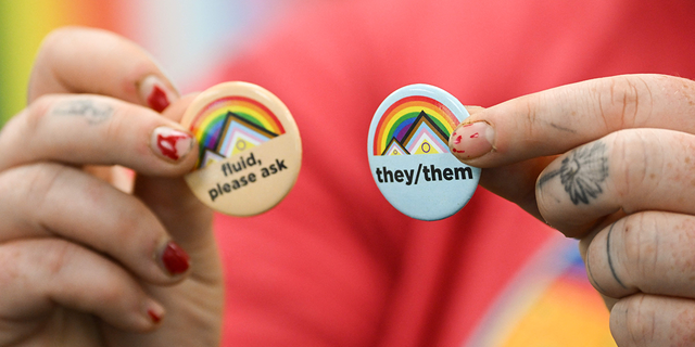 LGBTQ person holds pins about gender pronouns on the University of Wyoming campus on August 13, 2022. (Photo by PATRICK T. FALLON/AFP via Getty Images)