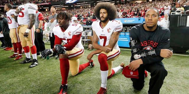 49ers quarterback Colin Kaepernick (center) takes a knee during an NFL game to protest police brutality.