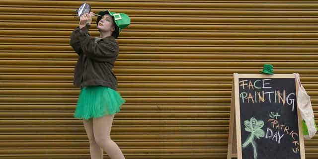 A woman applies eye shadow ahead of the St Patrick's Day Parade in Dublin, Ireland, on March 17, 2023. 