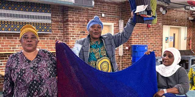 Mochozi Bigelegele, left, and Martha Mlebinge, center, both originally from Congo, and Fatuma Hussein, right, originally from Burundi, hold handmade blankets they picked out at a Welcome Blanket giveaway event on March 21, 2023, in Burlington, Vermont. 