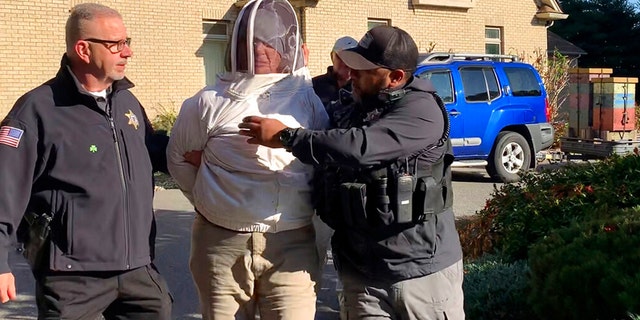 Rorie S. Woods, 55, of Hadley, Mass., center, wears a beekeeping suit while being taken into custody by Hampden County Sheriff's Department officers, in Longmeadow, Mass. Woods is accused of unleashing bees on sheriff's deputies serving an eviction notice, one of many bizarre crimes in 2022. 