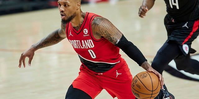 Portland Trail Blazers guard Damian Lillard drives to the basket in front of Los Angeles Clippers guard Terance Mann during the first half of a game in Portland, Ore., Oct. 29, 2021.