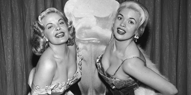 Cleo Moore, left, and Jayne Mansfield pose in front of an Oscar likeness at the Academy Awards circa 1956.