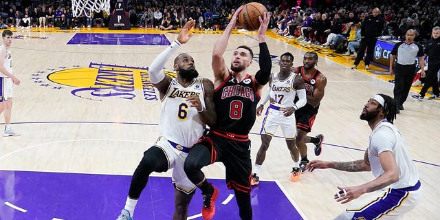 Chicago Bulls guard Zach LaVine, #8, drives to the basket between Los Angeles Lakers forward LeBron James, left, and forward Anthony Davis during the second half of an NBA basketball game, Sunday, March 26, 2023, in Los Angeles.