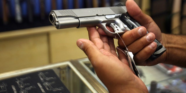 A man chooses a gun at the Gun Gallery in Glendale, California.
