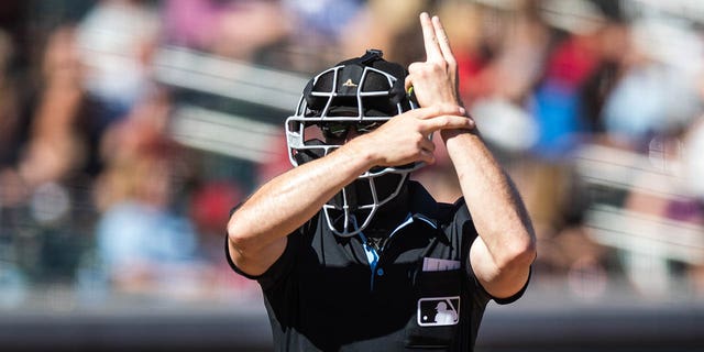 Umpire Matt Brown signals for a pitch clock violation during a spring training game between the Arizona Diamondbacks and the Colorado Rockies at Salt River Fields at Talking Stick March 12, 2023, in Scottsdale, Ariz. 