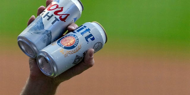 A beer vendor holds Coors Light and Miller Lite beer cans at American Family Field on June 24, 2022, in Milwaukee, Wisconsin.