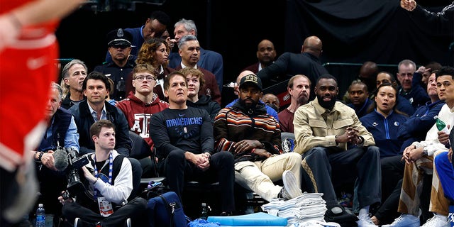 From left: Dallas Mavericks owner Mark Cuban and guards Kyrie Irving and Tim Hardaway Jr. sit courtside during the game against the Chicago Bulls at American Airlines Center in Dallas on April 7, 2023. 