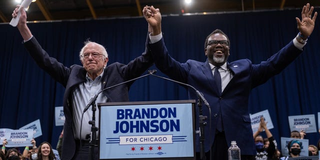 Progressive mayoral candidate Brandon Johnson and Bernie Sanders raise their hands to a crowd of supporters at Johnson's rally at the UIC Forum on March 30, 2023.