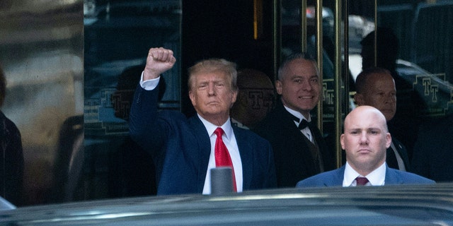 Former US president Donald Trump raises his fist as he arrives in the Manhattan court for his arraignment.