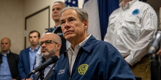 Greg Abbott sitting at a table with a microphone