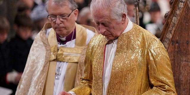 King Charles III holding the Sword of State during his coronation ceremony in Westminster Abbey