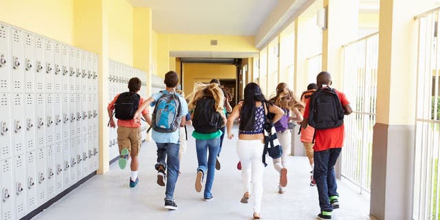 Group of high school students running down corridor.