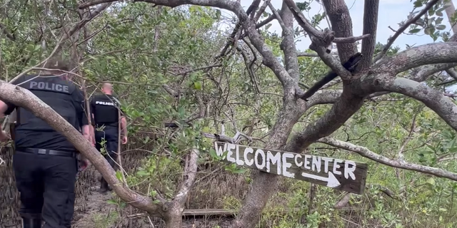 police walk by welcome sign on island